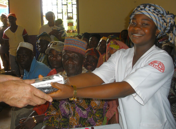 An african nurse smiling and being handed equipment