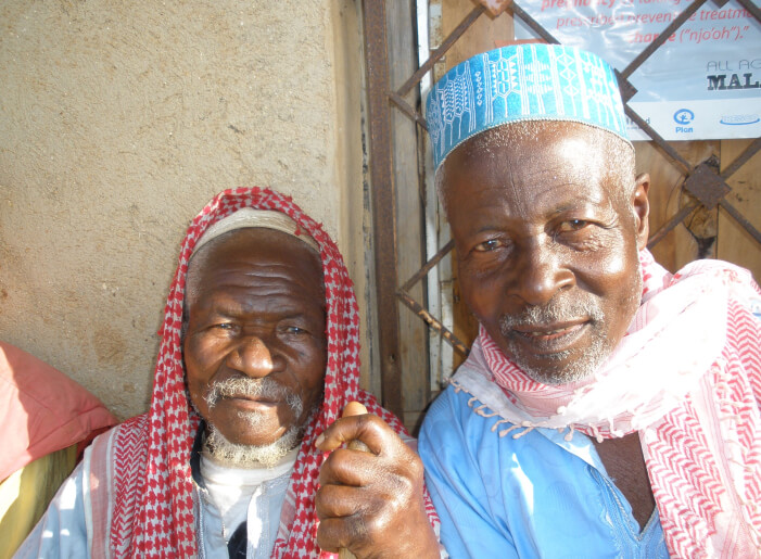 Two male african villagers in traditional clothing looking at the camera and smiling